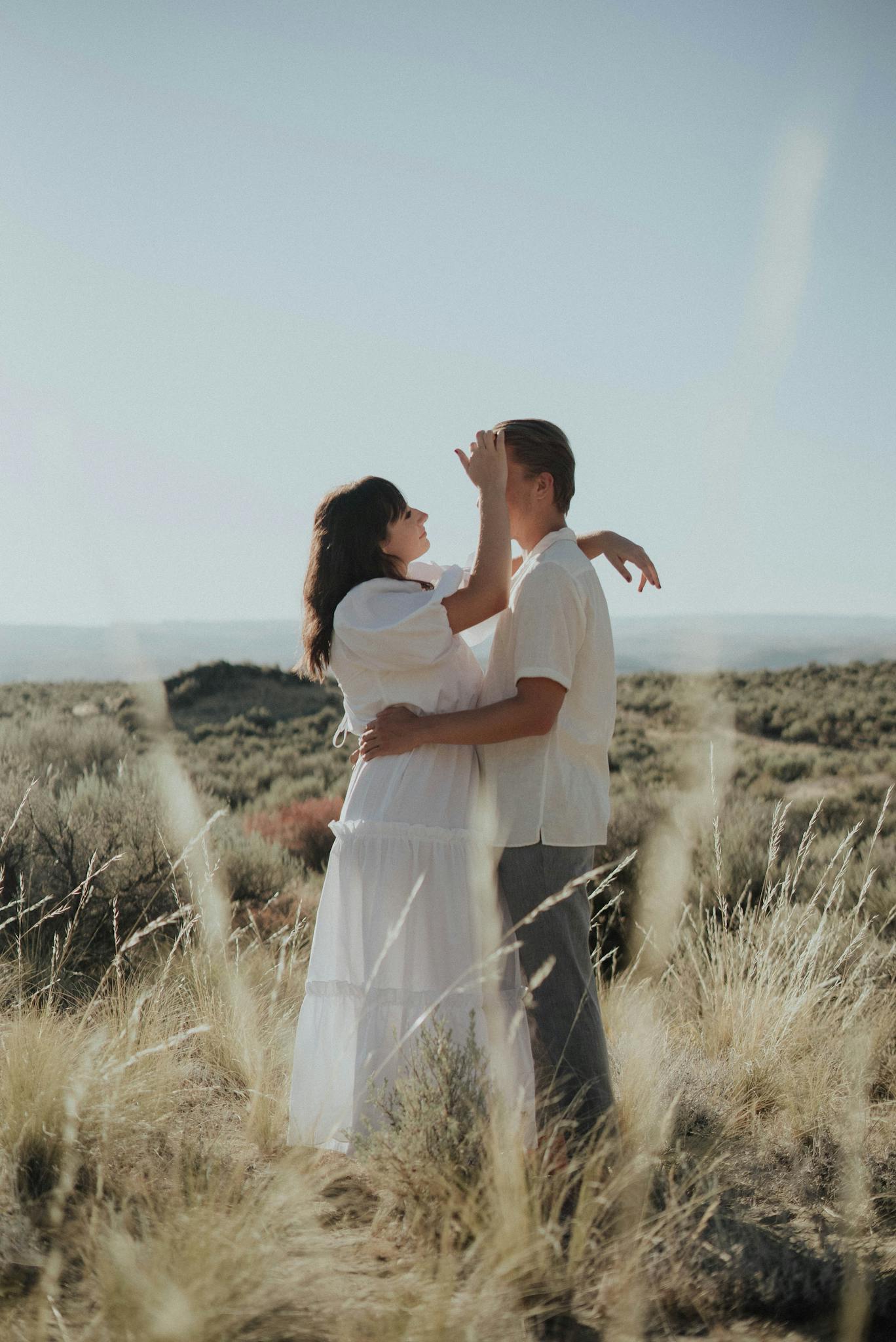 Happy couple in stylish outfits embracing in nature in sunny day